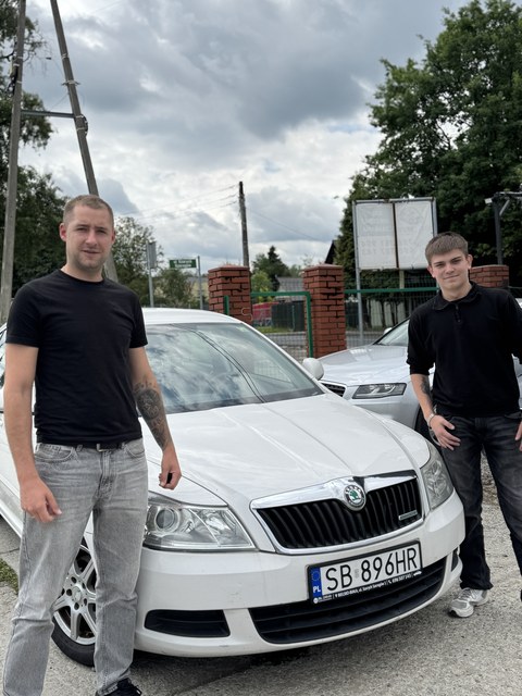 Dwóch klientów przy białym sedanie