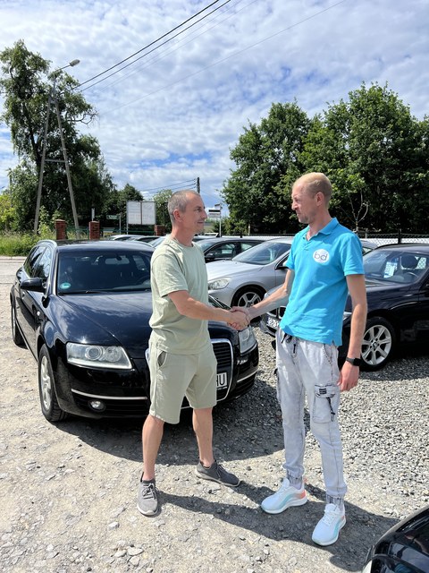 Dwóch klientów przy czarnym sedanie